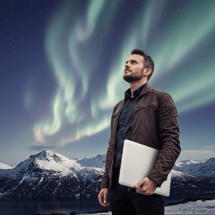 Man holding laptop looking up at northern lights with snow covered mountains in background after establishing branding with elevation tech